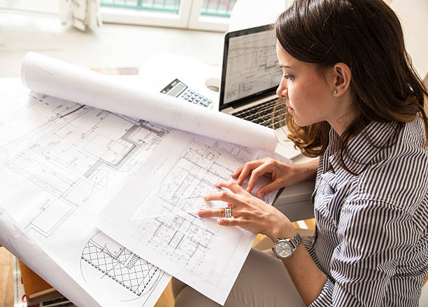 female architect working at home.she looking at blueprint.